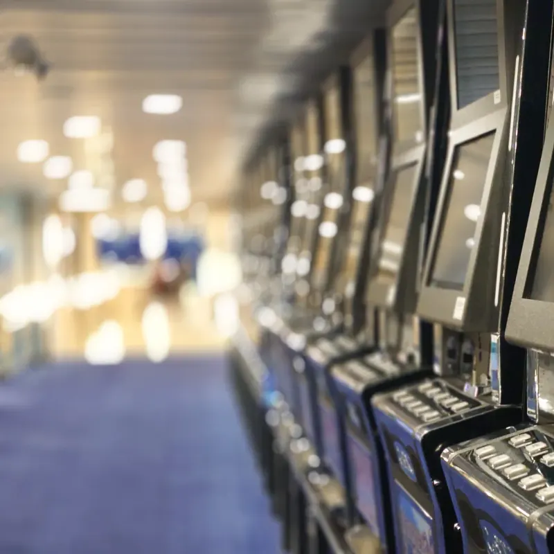 Row of slot machines with lit screens along a blue-carpeted aisle